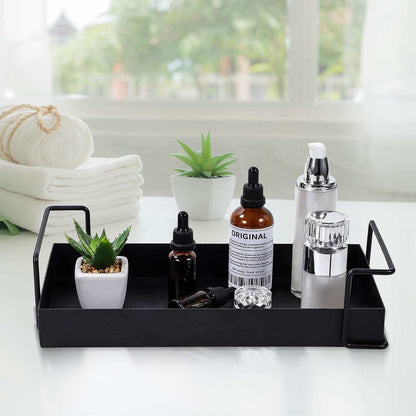 Black metal bathroom vanity tray with essential oils and decor items on a white countertop.