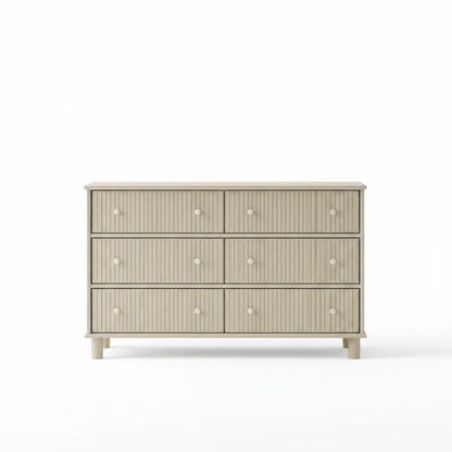 Beige dresser with decorative items in a room with a mirror and curtains.