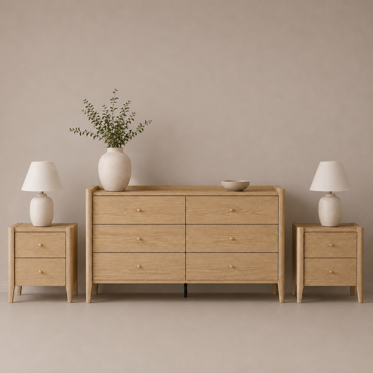 A light oak wood furniture set featuring a six-drawer dresser, a two-drawer nightstand on the left, and a matching two-drawer nightstand on the right, styled with white table lamps, a white ceramic vase with greenery, and a small bowl against a neutral beige background.