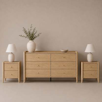 A light oak wood furniture set featuring a six-drawer dresser, a two-drawer nightstand on the left, and a matching two-drawer nightstand on the right, styled with white table lamps, a white ceramic vase with greenery, and a small bowl against a neutral beige background.