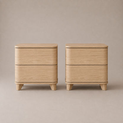 Two matching light oak wood nightstands with rounded edges, two drawers each, and short tapered legs, shown side by side against a warm beige studio background.